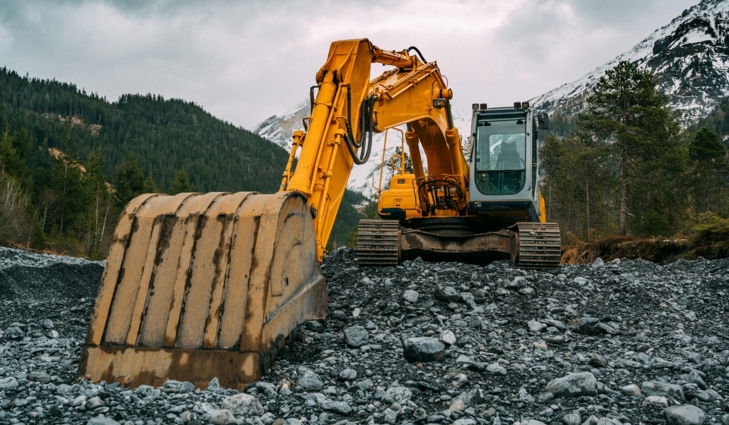 yellow and black excavator on rocky ground